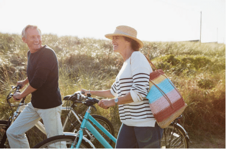 un homme et une femme marchant à côté de leur vélo à la campagne